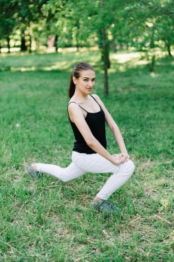 Genç güzel kız parkta egzersizleri yapıyor