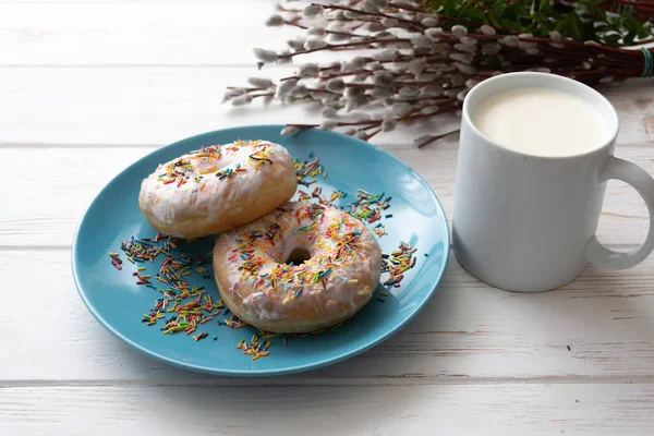Пончики на голубой тарелке с чашкой молока на белом деревянном фоне — стоковое фото