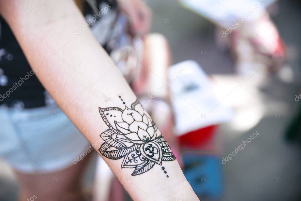 Painting henna with patterns on the arm on the wrist of a woman's hand