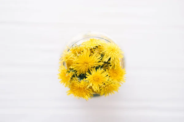 Dandelions in a glass jar on a white background — Stock Photo, Image