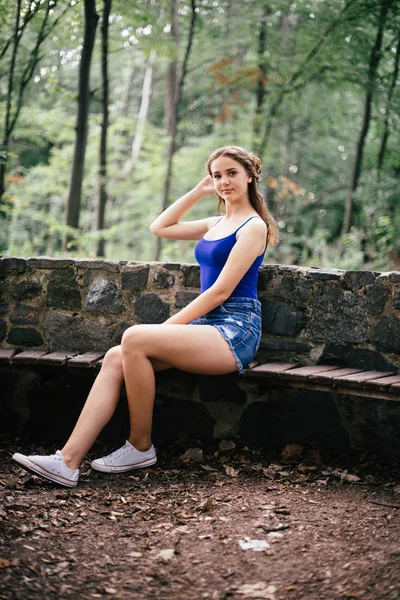 Hermosa Chica Pantalones Cortos Chaleco Azul Sentado Frontera Piedra —  Fotos de Stock