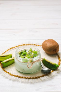 Kivi dilimleri ahşap beyaz zemin üzerine yoğurtlu.