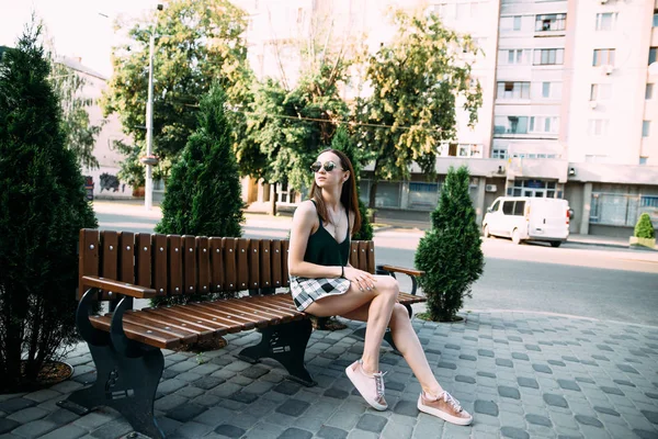 Een meisje in een zwarte shirt en broek in een park op een bankje — Stockfoto