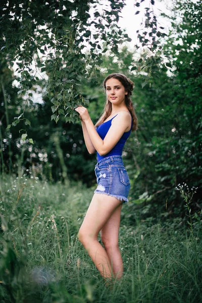 Bella ragazza in pantaloncini corti e una t-shirt blu nel bosco — Foto Stock