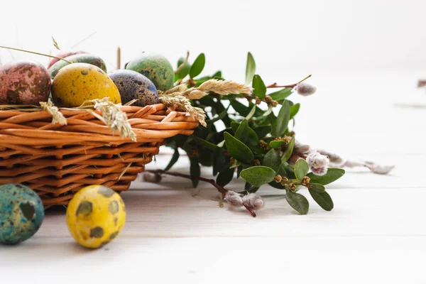 Uova di Pasqua in un cesto su uno sfondo di legno bianco — Foto Stock