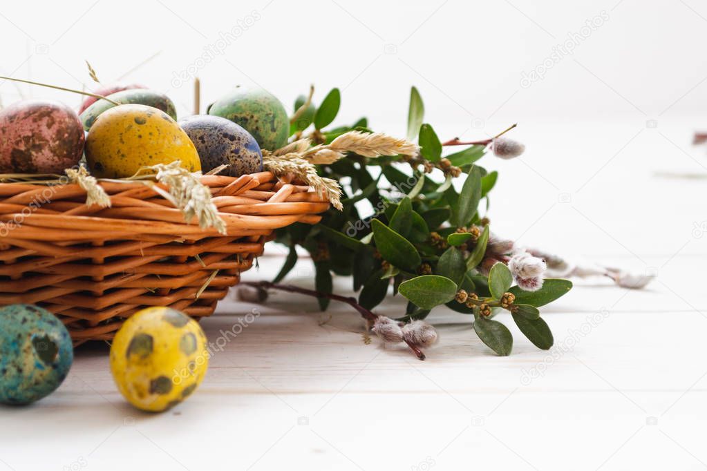 Easter eggs in a basket on a white wooden background