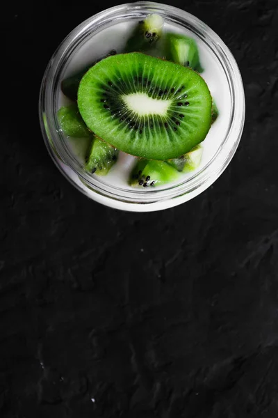 Yogurt with kiwi slices on black background