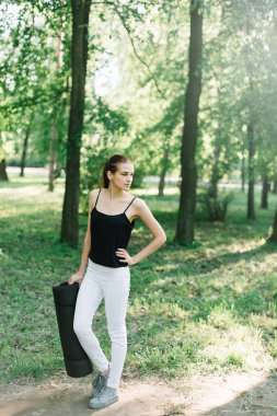 Elinde bir karemat ile kız atlet parkta yürüyor