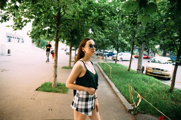 Brünettes Mädchen an einem Sommertag in der Stadt mit runder Sonnenbrille — Stockfoto