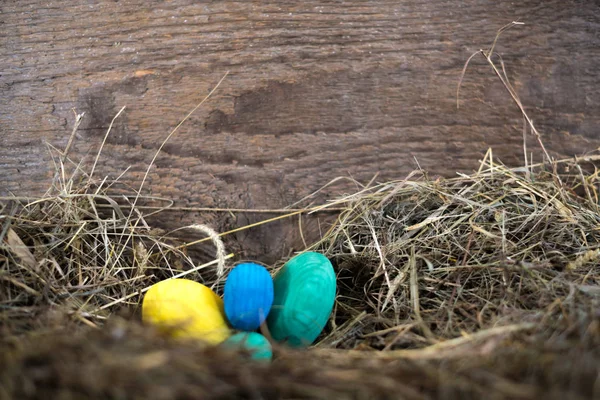 复活节彩蛋放在一个有模糊背景的干草上的篮子里 — 图库照片