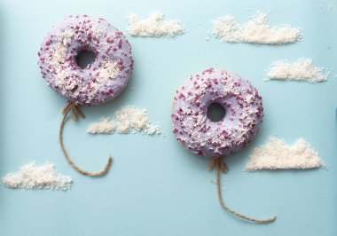 Kavram mor donuts bulutlar minimalizm ile mavi bir arka plan üzerinde