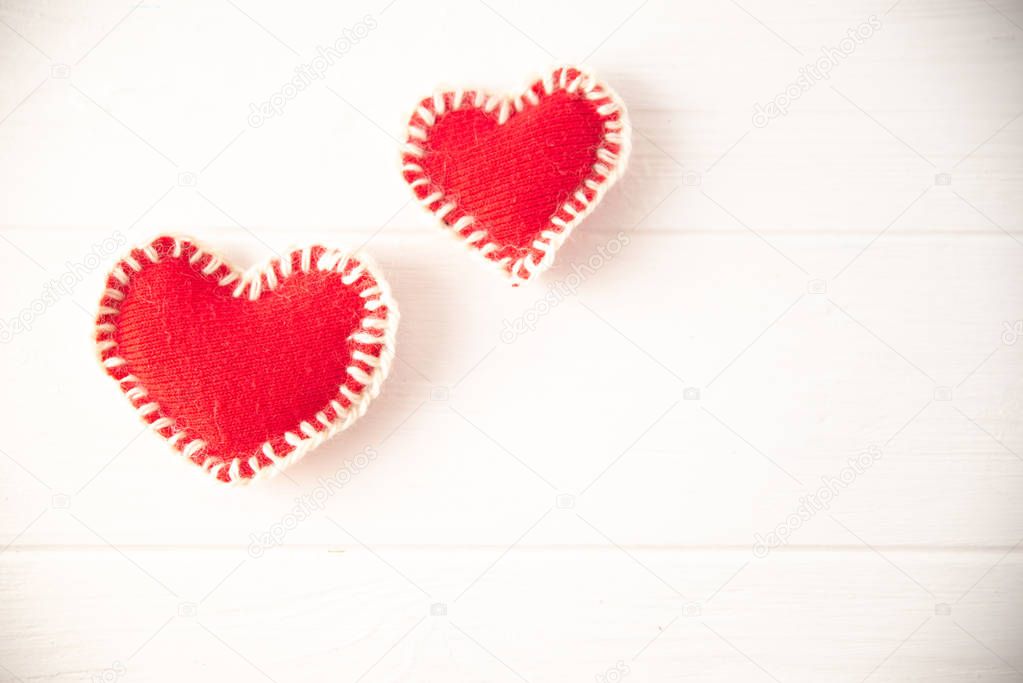 Red knitted soft fabric hearts on white background