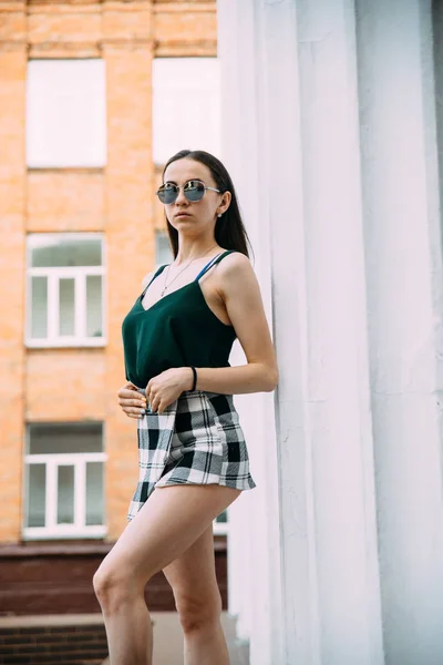 Sexy girl in sunglasses t-shirt and short shorts near the columns — Stock Photo, Image