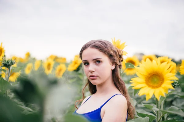 Menina bonita no campo com girassóis em shorts curtos e um colete — Fotografia de Stock