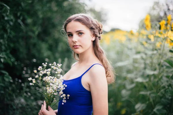 Dívka v krátkých šortkách a modré tričko s kytice divokých květů — Stock fotografie