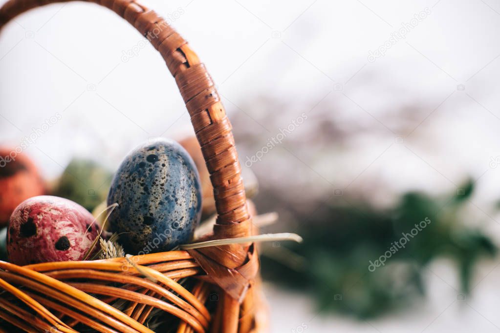 Easter eggs in a basket on a white wooden background