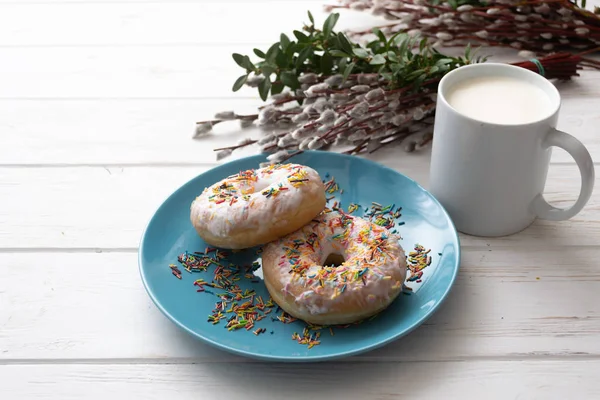 Donuts on a blue plate with a cup of milk on a white wooden background — Stock Photo, Image