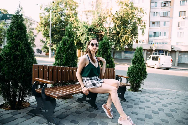 Een meisje in een zwarte shirt en broek in een park op een bankje — Stockfoto