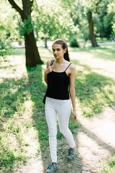 Flickan idrottare med en karemat i hennes händer promenader i parken — Stockfoto