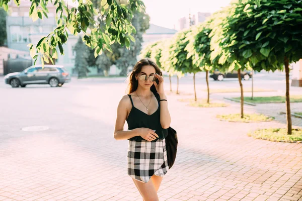 Ragazza bruna in una giornata estiva in città indossando occhiali da sole rotondi — Foto Stock