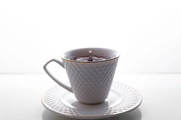 Tea splashes in a cup on a white background