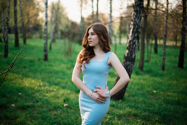 Schöne junge Mädchen in einem blauen Kleid in einem Frühlingspark — Stockfoto