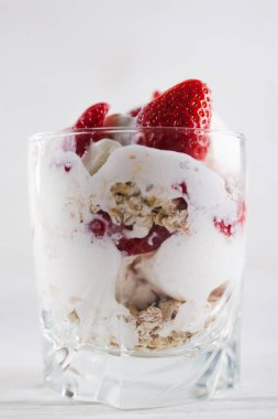 Beyaz ahşap arka planda dondurma ve dondurma tabağında çilekli tatlı.