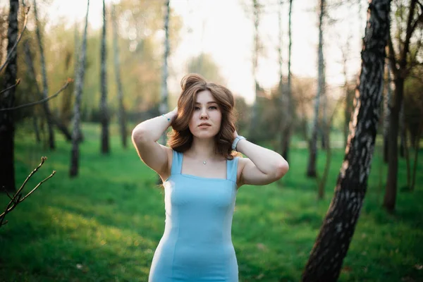 Gyönyörű fiatal lány kék ruhában egy tavaszi parkban — Stock Fotó