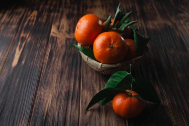 Ahşap arka planda yaprakları olan taze mandalinalar.