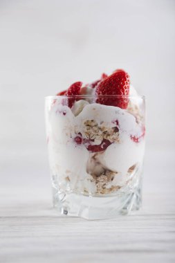 Beyaz ahşap arka planda dondurma ve dondurma tabağında çilekli tatlı.