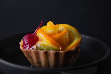 Siyah arka planda turuncu peynirli tatlı.