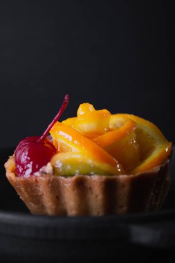 Siyah arka planda turuncu peynirli tatlı.