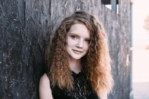 Menina ruiva em um vestido preto perto de uma parede texturizada escura — Fotografia de Stock