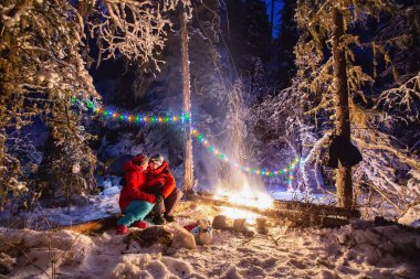 Kadın ve erkek, kışın Noel ağacının altında, ormanın ışıklarıyla, yeni yılın gelişiyle, Noel yakında gelecek ve yeni yıl, tatille birlikte, bayram yakında gelecek.
