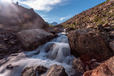 Güneşli baharda kayalık dağlarda akan hızlı dağ deresinin resimsel görüntüsü 