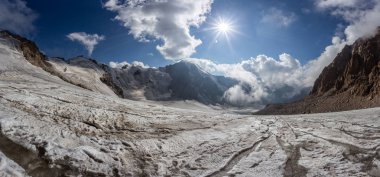 Karlı dağ manzarası güneşli bir havada kayalık yamaçtan geçer. 