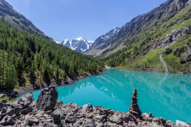 Mavi nehir manzarası ve Tien Shan dağlarının karlı tepeleri baharda güneşli bir günde. 