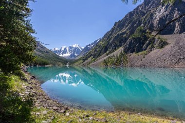 Mavi nehir manzarası ve Tien Shan dağlarının karlı tepeleri baharda güneşli bir günde. 