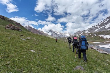 Kırgızistan Yazı. Bir grup turist sırt çantalarıyla yamaçlarda dağ yürüyüşüne çıktılar..