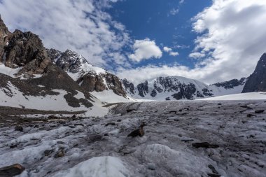 Karlı dağ manzarası güneşli bir havada kayalık yamaçtan geçer. 