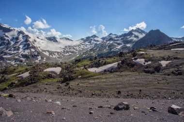 Güneşli baharda karlı tepede kayalık dağların manzarası 