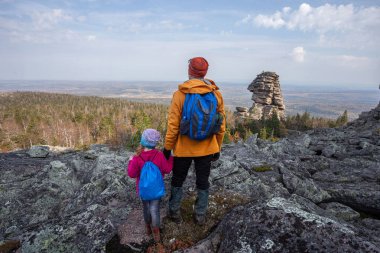 Babası kızıyla birlikte dağlarda kayalıklarda, kayalara tırmanıyor, ailesiyle, babasıyla dinleniyor. Açık havada.
