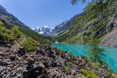 Mavi nehir manzarası ve Tien Shan dağlarının karlı tepeleri baharda güneşli bir günde. 