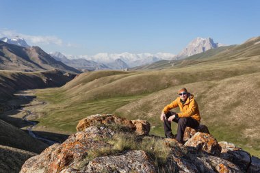 Dağların tepesinde oturan dağcı