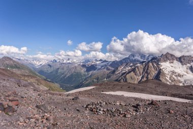 Güneşli baharda karlı tepede kayalık dağların manzarası 
