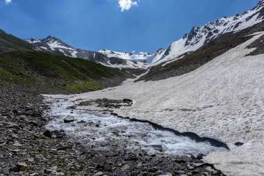 Güneşli baharda kayalık dağlarda akan hızlı dağ deresinin resimsel görüntüsü 