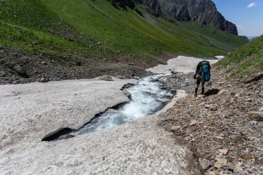 Güneşli kış günlerinde, sırt çantalı, karlı dağlarda yürüyüş yapan sıcak spor elbiseli bir gezgin. 