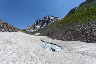Güneşli baharda kayalık dağlarda akan hızlı dağ deresinin resimsel görüntüsü 