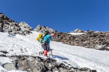Güneşli kış günlerinde, sırt çantalı, karlı dağlarda yürüyüş yapan sıcak spor elbiseli bir gezgin. 