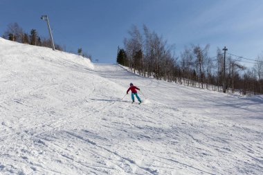 Kadın kayakçı dağların yamacında kayıyor.